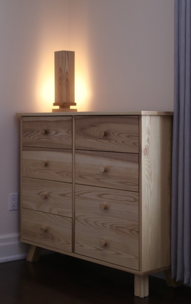 A wooden table lamp on a dresser. 