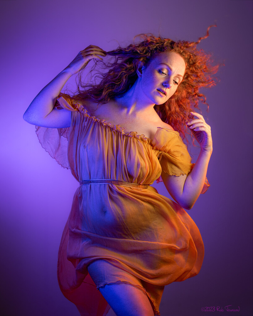 a photo of art model ivory flame in a yellow dress against a purple background.