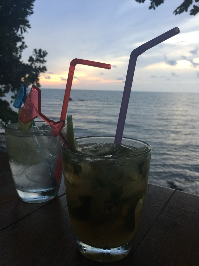 Two cocktails in the foreground, a calm tropical sea in the background