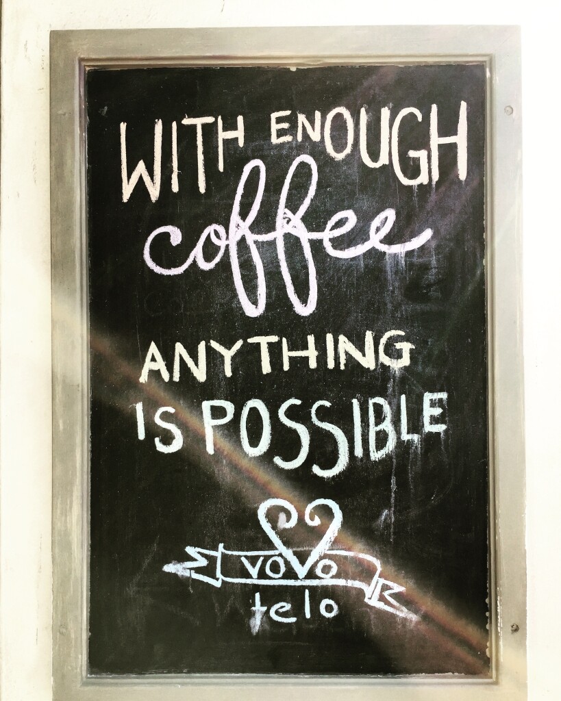Hand-written sign for Vovo Telo cafe in Cape Town‘s waterfront reading “with enough coffee anything is possible”.