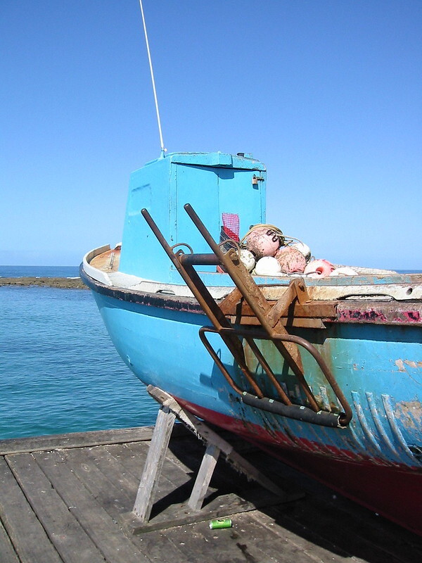 An old fishing boat on the Lorne pier. The boat is painted sky blue, the sky behind is the same blue, as is the sea