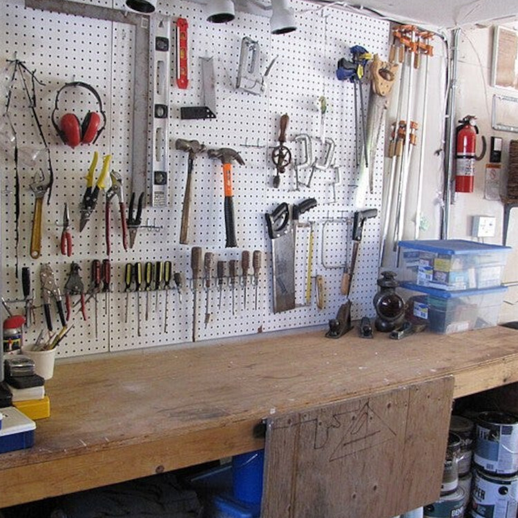 A workbench with a pegboard behind it. from the pegboard hang an array of hand-tools.


Image:
btwashburn (modified)
https://commons.wikimedia.org/wiki/File:Garage_Workbench_-_%281%29.jpg

CC BY 2.0
https://creativecommons.org/licenses/by/2.0/deed.en
