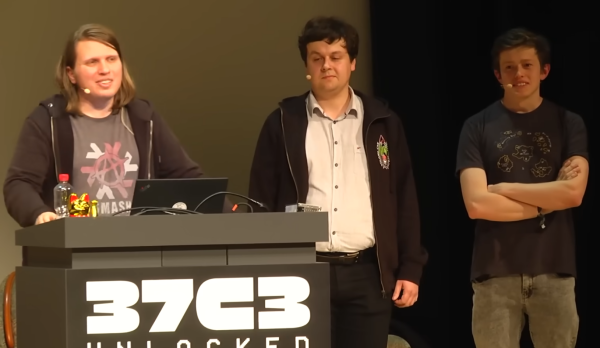 37C3 stage showing three people:

1. A long-haired q3k with a Nix 'smash the state' tshirt and 37C3 hoodie standing at the podium.
2. A short haired mrtick in a button-up long sleeve shirt and a Poland Can Into Space hoodie looking disappointed at q3k.
3. A short-haired redford in a Plaid CTF tshirt with his arm crossed listening to an audience question.