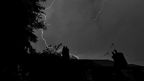 black & white photo of lightning above a house