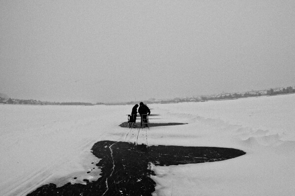 two people with kick sledges on a frozen lake, in black & white