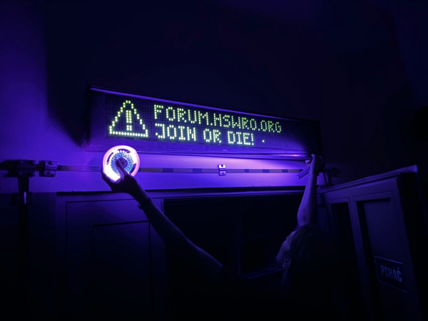 Flipdot display in hackerspace Wrocław showing text "forum.hswro.org hoin or die!" 