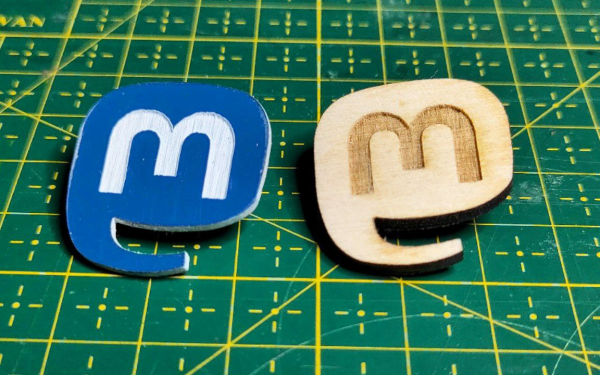 Przypinki z logo mastodon leżą na macie do cięcia