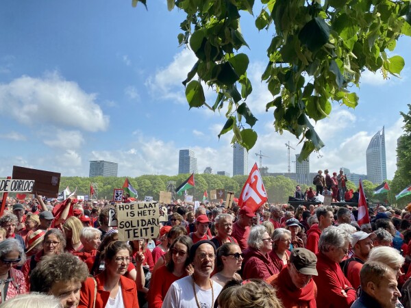 Protestors, dressed in red, on thr Malieveld, with a view on central station and the government offices