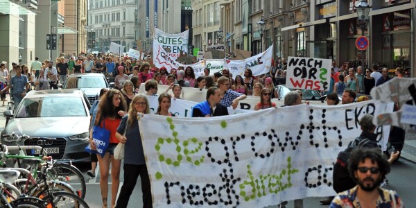 People marching through the streets with a banner saying "degrowth needs direct action" during a demonstration in Liepzig in 2014.