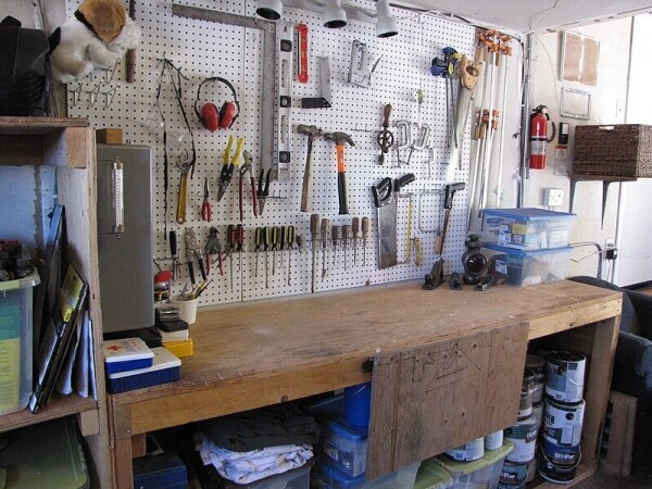 A workbench with a pegboard behind it. from the pegboard hang an array of hand-tools.


Image:
btwashburn (modified)
https://commons.wikimedia.org/wiki/File:Garage_Workbench_-_%281%29.jpg

CC BY 2.0
https://creativecommons.org/licenses/by/2.0/deed.en
